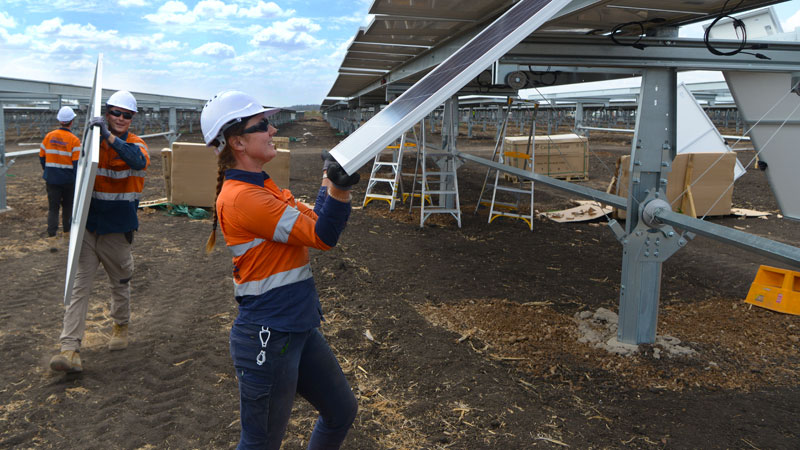 girl moving solar panel into place for large solar array installation